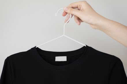 A Person Holding a Clothes Hanger with a Blank Shirt Label